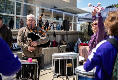 A bagpiper performs alongside a marching drummer at an outdoor Drum Jawn event