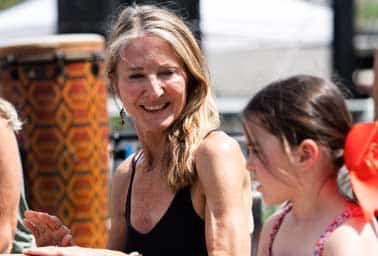 A woman smiles warmly at a young girl outdoors during a community wellness event