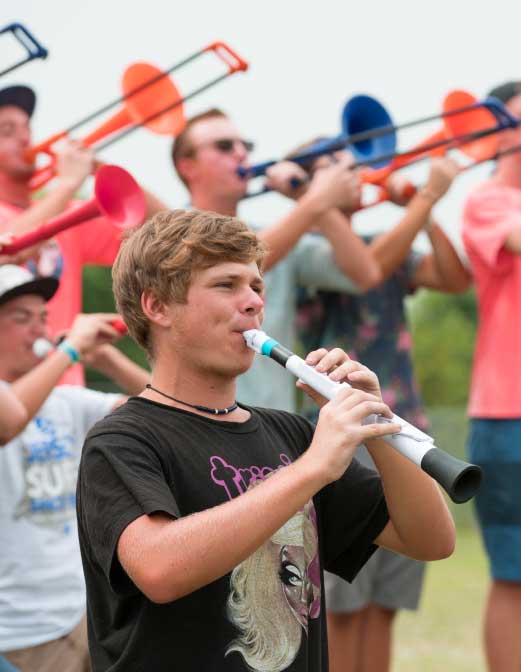 Students play colorful plastic horns together outdoors during an instrument discovery activity